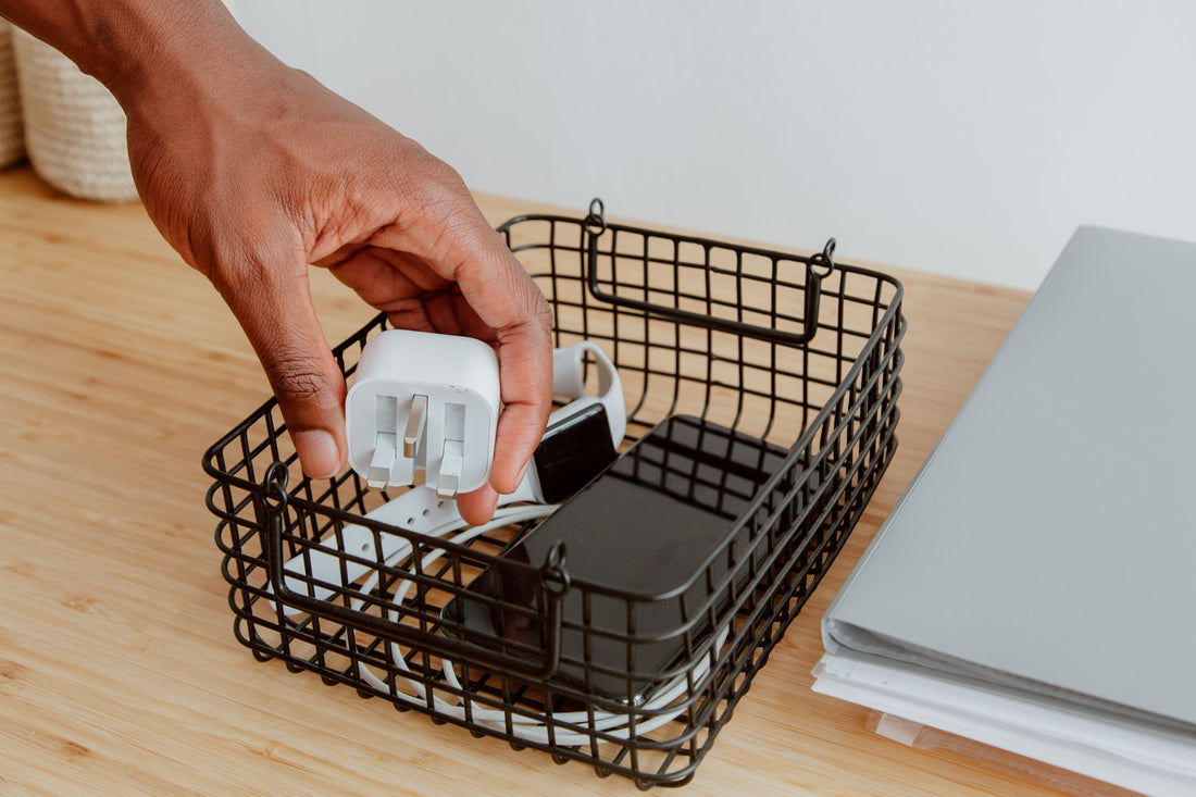 Hand placing a charger into a desk organizer basket