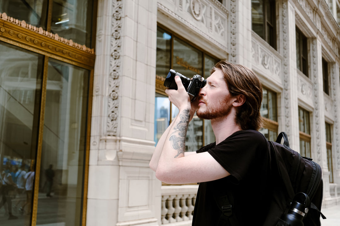 Photographer with a backpack taking a photo on a city street