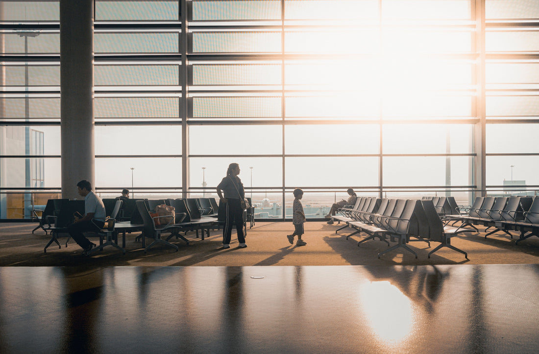 Parent and child walking through a sunlit airport terminal