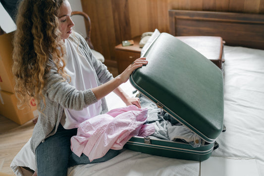 Traveler closing a packed suitcase on a bed before a trip